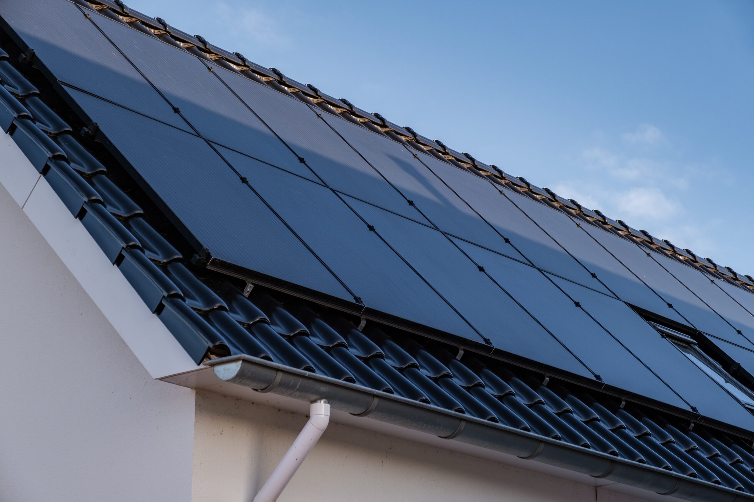 Newly build houses with solar panels attached on the roof against a sunny sky Close up of new building with black solar panels. Zonnepanelen, Zonne energie, Translation: Solar panel, , Sun Energy